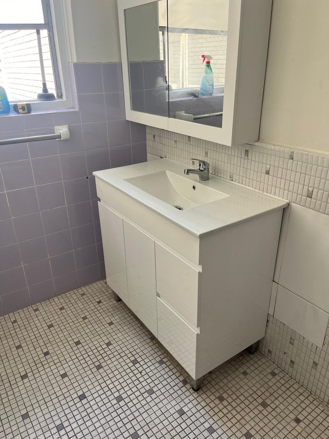 Newly installed white bathroom vanity and mirror cabinet